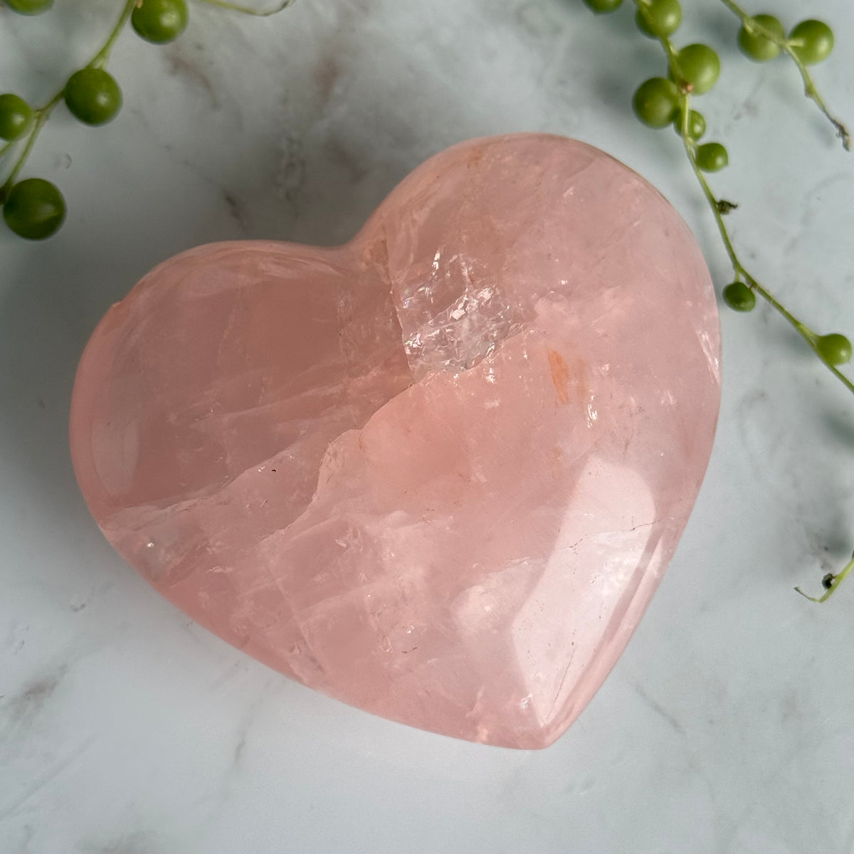 Rose Quartz heart carving held in hand for scale