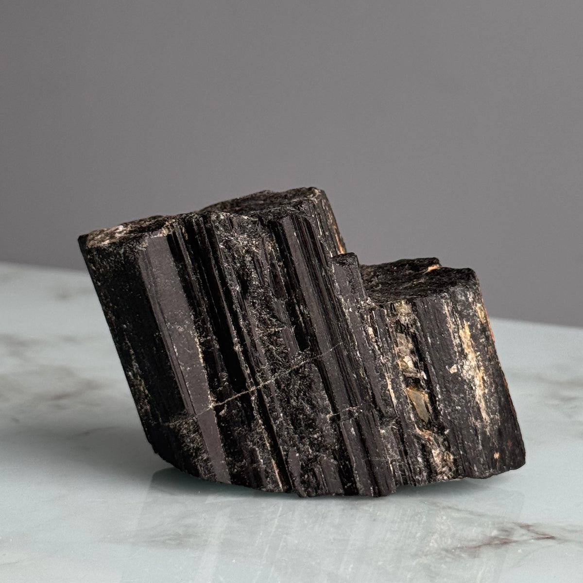 Black Tourmaline raw crystal specimen held in hand for scale