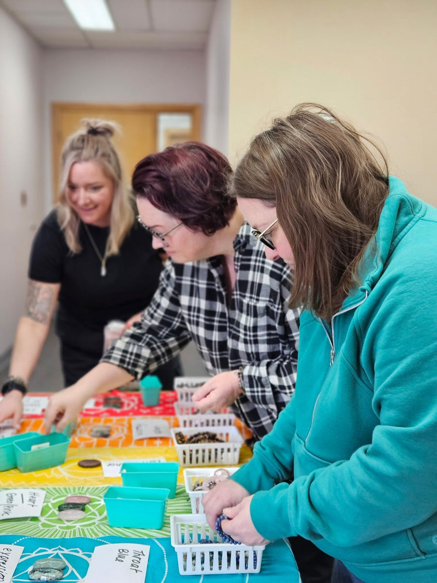 Three guests choosing crystals for their necklaces at a group workshop