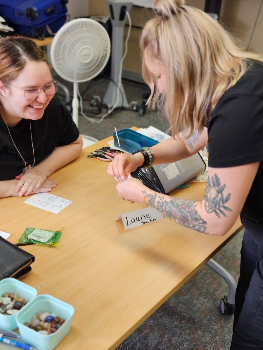 Laurie guiding a guest through wire wrapping at a crystal necklace workshop