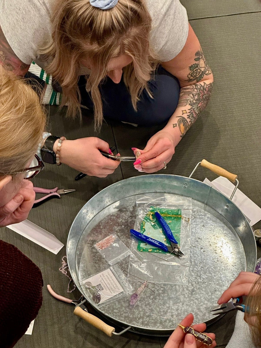 Guests learning to wire wrap crystal pendants during a workshop