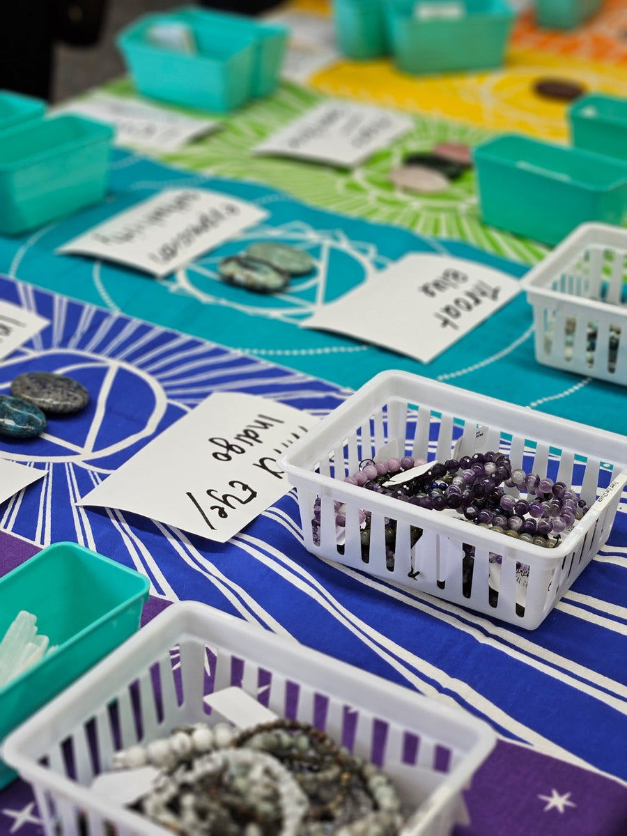 Baskets of crystals and labelled stone meanings on the workshop table